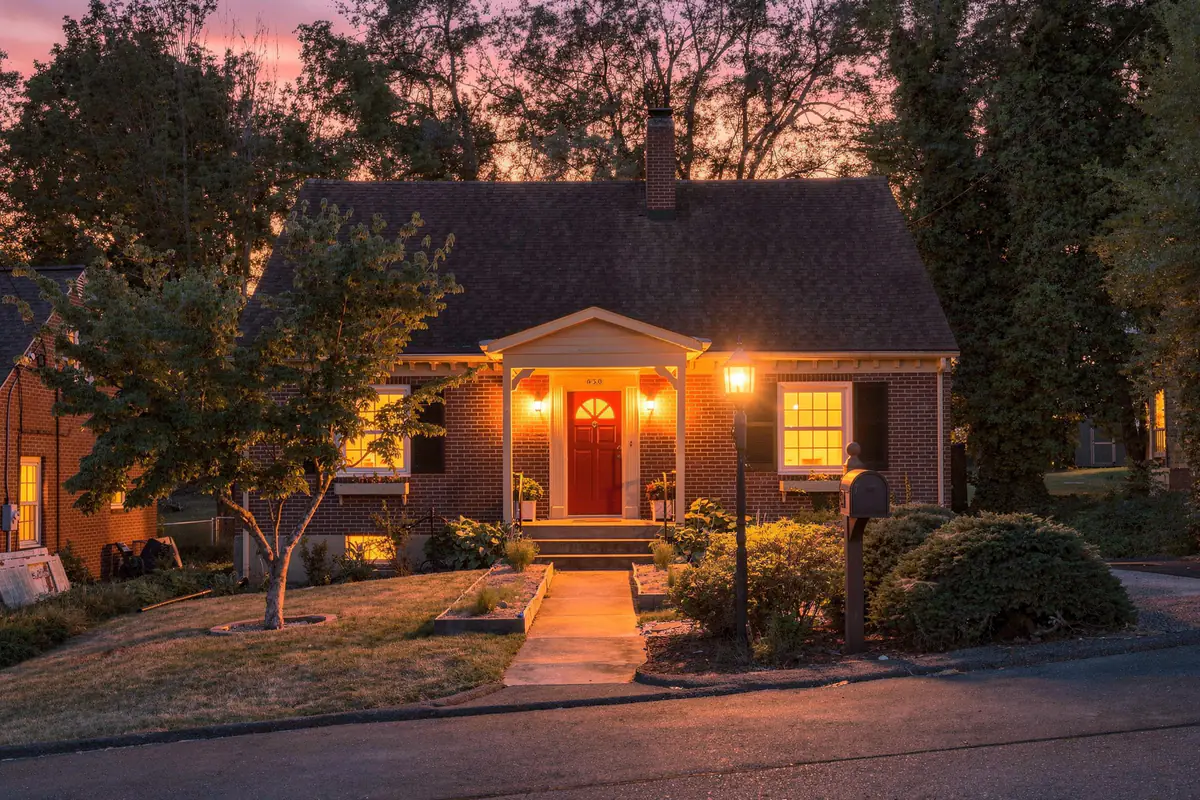 Twilight photo of a brick cottage with glowing windows, Staunton VA